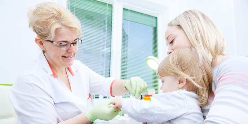 Meningokoki - objawy, leczenie, szczepienie. Mama z dzieckiem podczas wizyty lekarskiej.